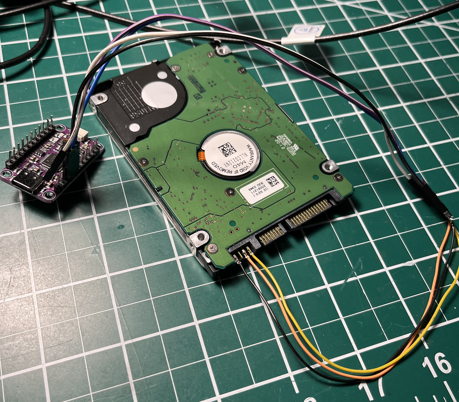 HDD circuit board showing 4-pin RS232 serial interface pins located next to SATA connector for diagnostic access